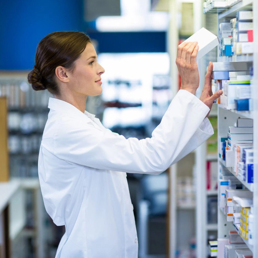 Apothekerin prüft Medikamente im Regal